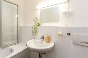 A bathroom with a white sink, a mirror, a towel rack, and a handheld showerhead. - FullHouse | Halle | R6 Amsterdam (Halle (Saale))