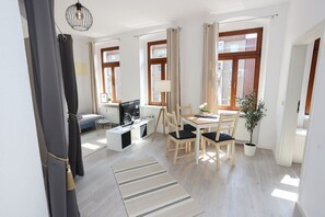 Ein modernes Wohnzimmer mit einer Couch, einem Fernseher, einem Esstisch und Stühlen.