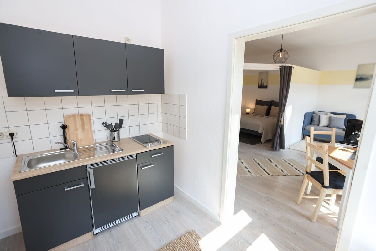 A modern kitchen with black cabinets, a wooden countertop, and a built-in dishwasher.