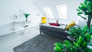 A modern bedroom with a bed, a desk, a chair, and a radiator. - FullHouse | Magdeburg | L10-4 | Loft-Flair (Magdeburg)