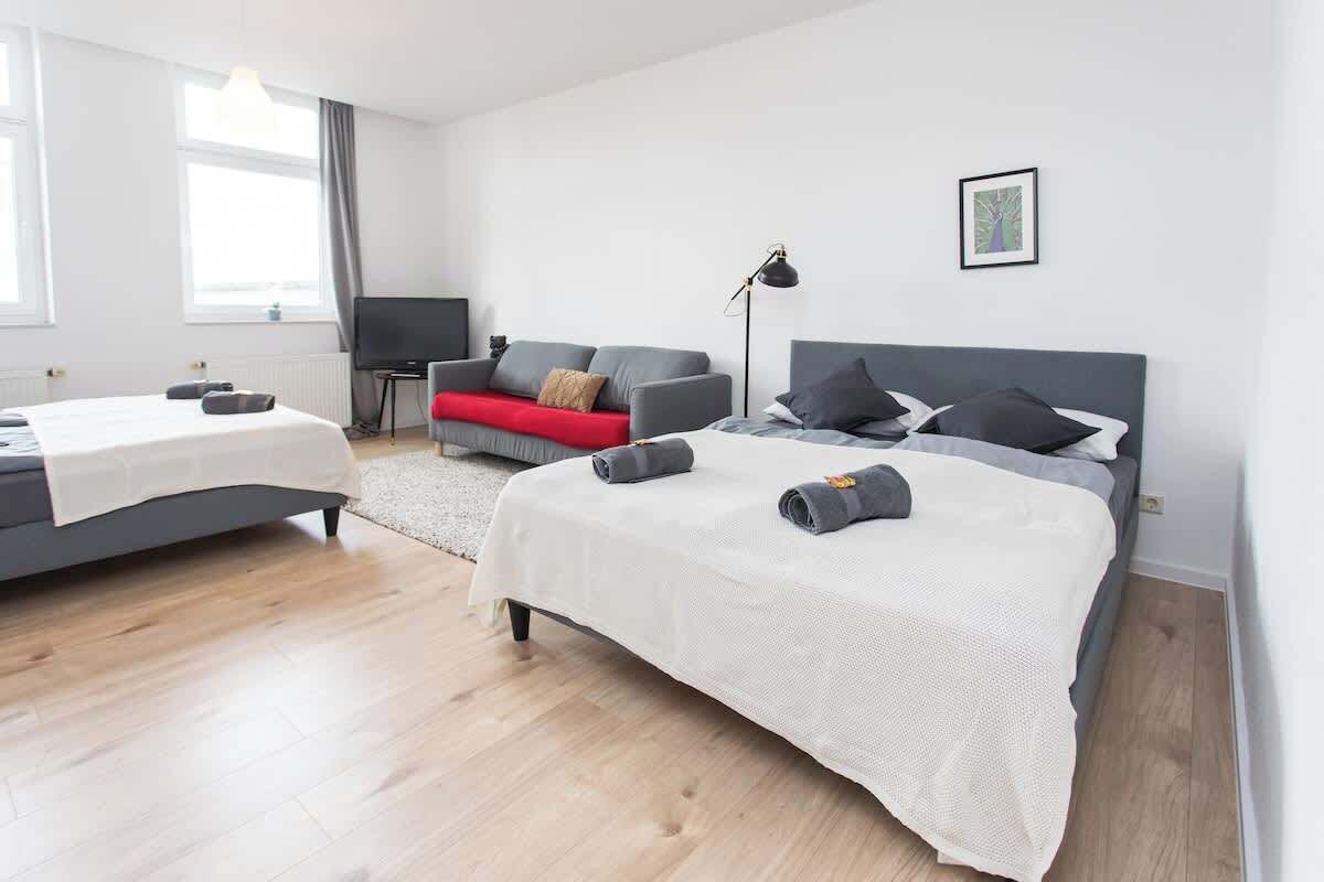 Una habitación de hotel moderna con una cama grande, un sofá, un televisor y un escritorio.