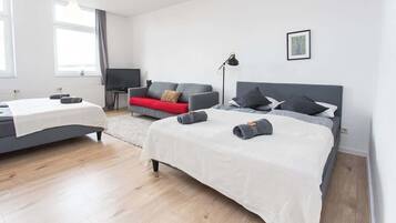 Una habitación de hotel moderna con una cama grande, un sofá, un televisor y un escritorio.