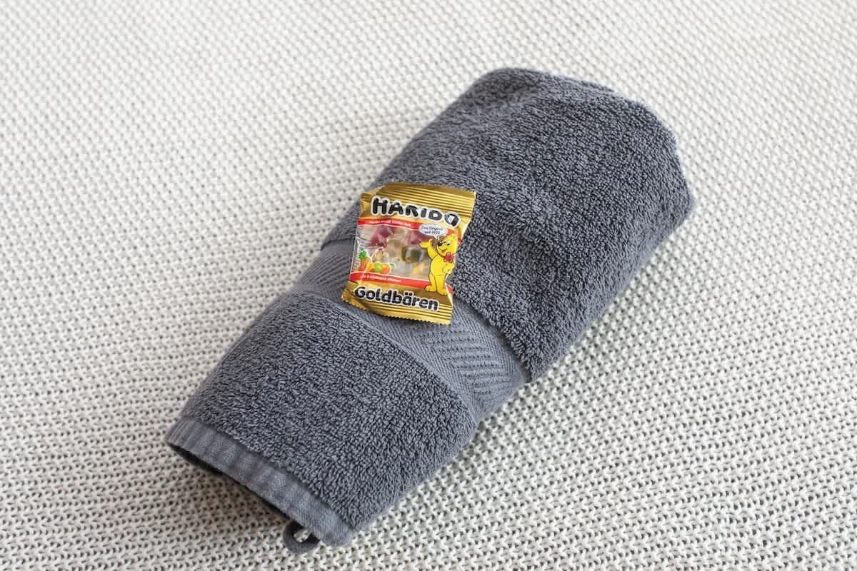 A rolled gray towel with a label reading "Haribo Goldbären."