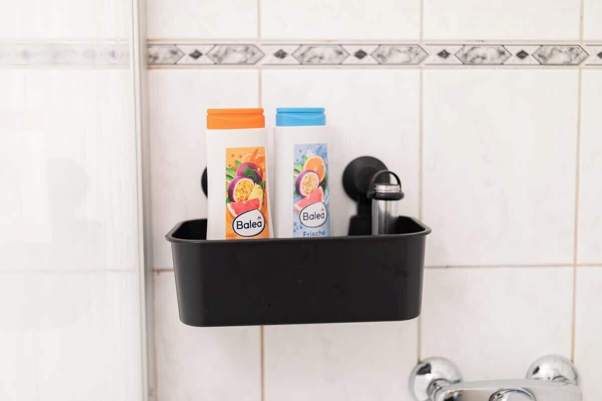 A black bathroom shelf with two toiletry bottles labeled "Balea" and "Balea Frische" against a tiled wall.