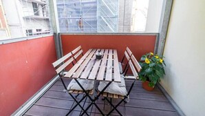 A small balcony with a wooden table and chairs, a potted plant, and a view of a building under construction. - FullHouse | M18-4 | Kings Palace (Erfurt)