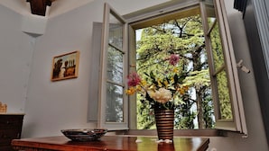 Een kamer met een houten tafel, een schaal, een vaas met bloemen en een schilderij aan de muur.