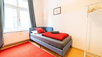 Ein modernes Schlafzimmer mit Bett, Heizkörper, einem Fenster mit Vorhängen und einem an der Wand befestigten Handtuchhalter.