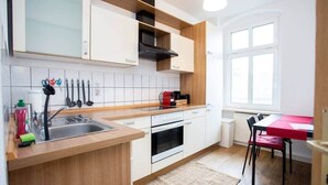 Una cucina moderna con mobili bianchi, un piano di lavoro in legno, forno integrato e una finestra che offre luce naturale.