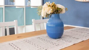 Un vaso blu con fiori su un tavolo con tovaglia bianca.