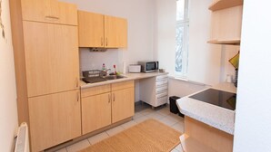 Una cucina compatta con mobili in legno, un forno a microonde e un lavandino.