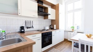 Una cocina moderna con armarios blancos, un lavamanos de acero inoxidable, un horno negro y una ventana con vistas al exterior.
