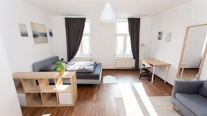 Una stanza moderna e luminosa con un letto, una scrivania, un divano e un grande specchio.