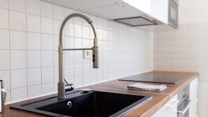 Una cucina moderna con un rubinetto in acciaio inossidabile, un lavello nero e un piano di lavoro in legno.