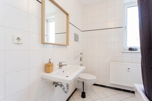 Un baño con lavamanos, espejo y retrete blancos.