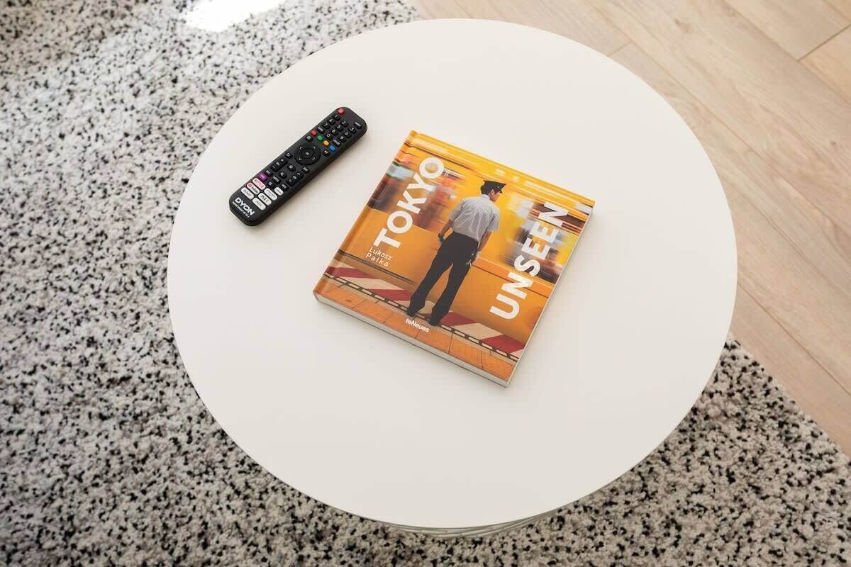 A book titled "TOKYO UNSEEN" on a white round table with a remote control beside it.