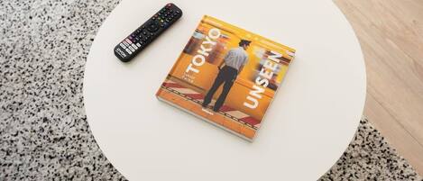 A book titled "TOKYO UNSEEN" on a white round table with a remote control beside it.