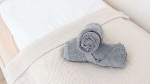 Una toalla gris doblada con cuidado sobre una cama beige con textura.