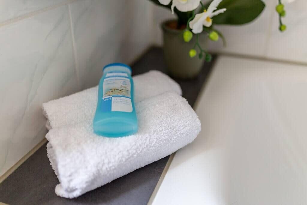 A bathroom with a white towel on a dark countertop, a blue bottle, and a potted plant with white flowers.