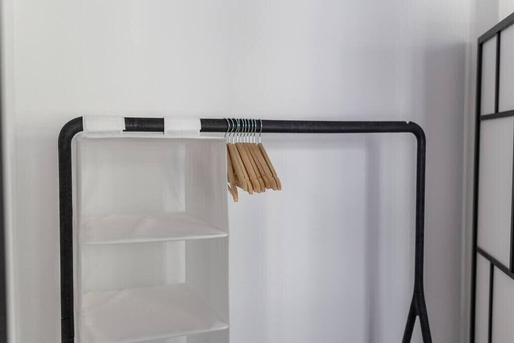 A black metal shelf unit with a white door and a hanging rack with wooden clothespins.