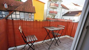 A balcony with a red safety net, two wooden chairs, and a small table. - FullHouse | K70 Goethe | Balcony | Washing Machine (Eisenach)