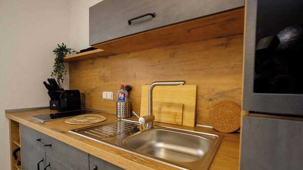 A modern kitchen with a wooden countertop, stainless steel sink, and a built-in oven. - FullHouse | K70 Goethe | Balcony | Washing Machine (Eisenach)