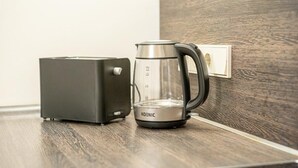 A modern kitchen with a toaster and a glass coffee maker on a wooden countertop.