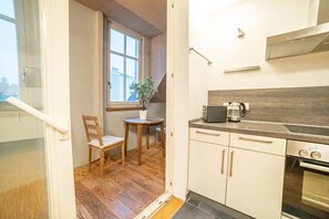 Une cuisine compacte avec un plancher en bois, une fenêtre, une petite table avec une plante et un four moderne.