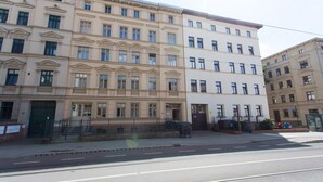 A multi-story building with a classical architectural style, featuring a central entrance with steps and a small garden area. - FullHouse | Halle | T28 Hawk Apt. (Halle (Saale))