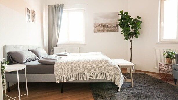 Une chambre à coucher avec un lit, une table de chevet et une plante en pot.