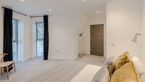 Een moderne slaapkamer met een bed, een stoel, een kledingkast, een deur en een vloerlamp.