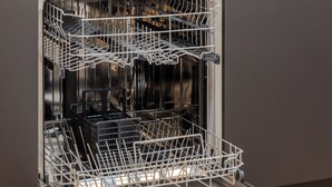 Een moderne keuken met een vaatwasser, een spoelbak en een schaal fruit op het aanrecht.
