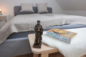Un dormitorio con una cama, una mesita de noche con un libro y una estatua.