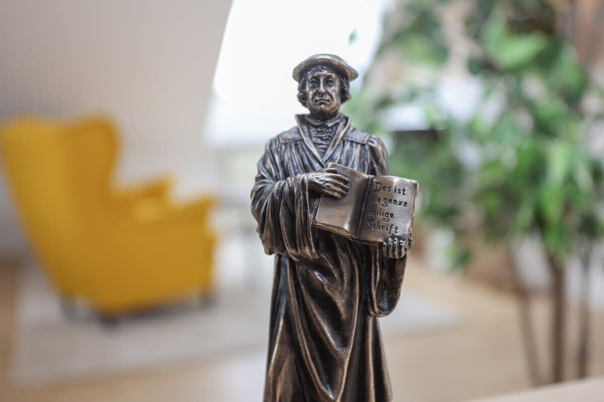 Une statue représentant un homme tenant un livre sur lequel est inscrit un texte.