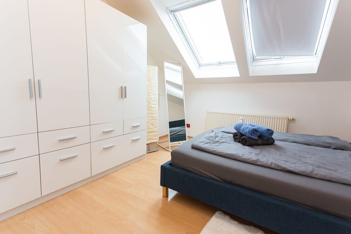A bedroom with a bed, a wardrobe, and skylights.