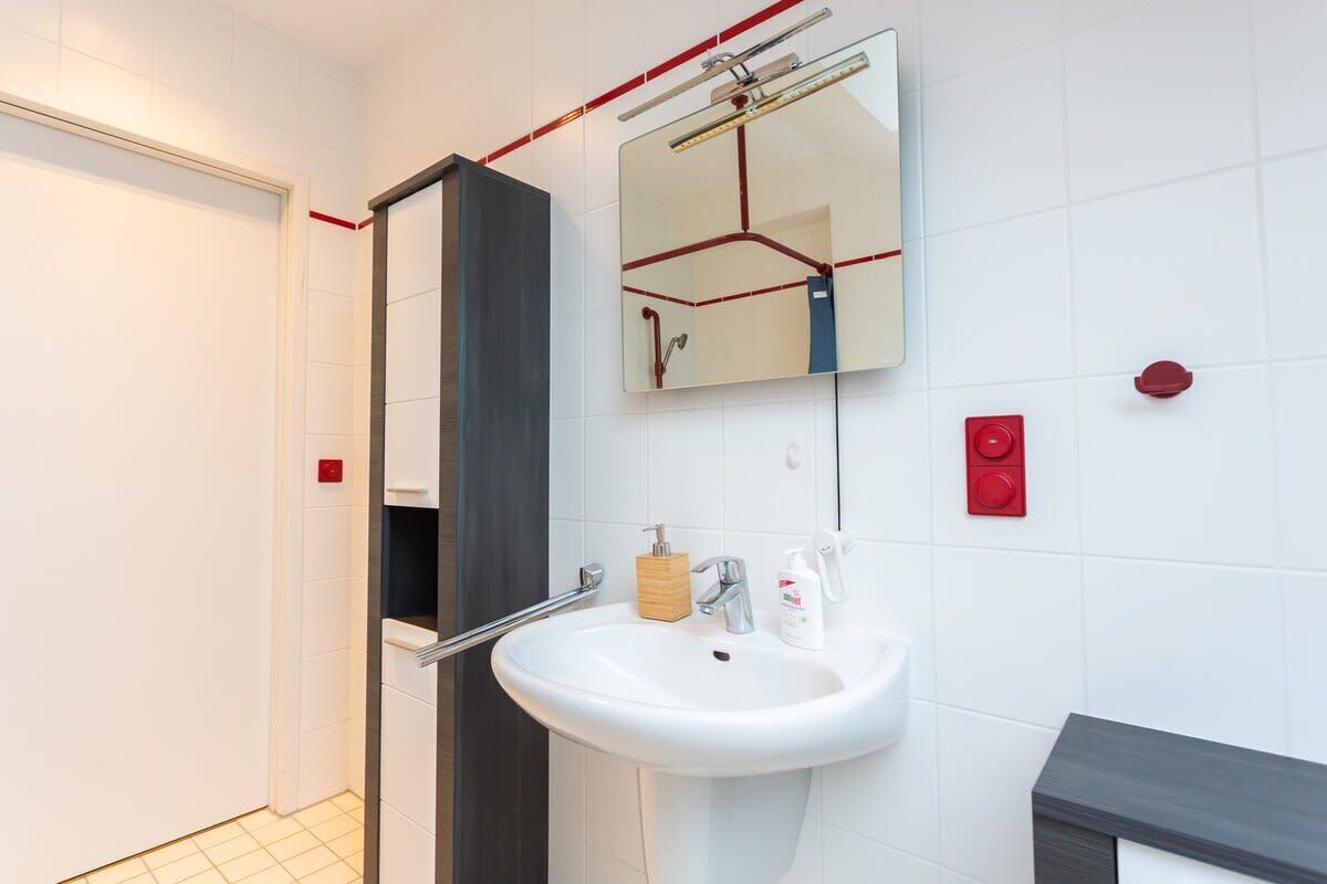 Une salle de bain moderne avec un lavabo blanc, un miroir et un espace douche.