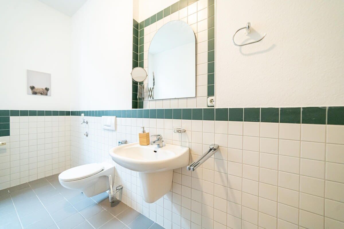 A bathroom with a toilet, sink, and mirror.