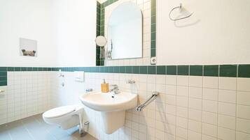 A bathroom with a toilet, sink, and mirror.