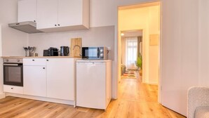 A compact kitchen with white cabinets, a microwave, a coffee maker, and a small refrigerator. - FullHouse Premium Apt. H11 (Leipzig)