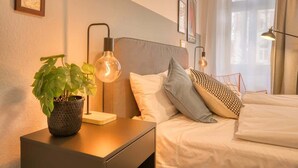 A neatly arranged bedroom with a bed, bedside tables, a lamp, and a potted plant. - FullHouse Premium Apt. H11 (Leipzig)