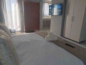 Une chambre d’hôtel avec un lit, un téléviseur fixé au mur, une armoire et une porte.
