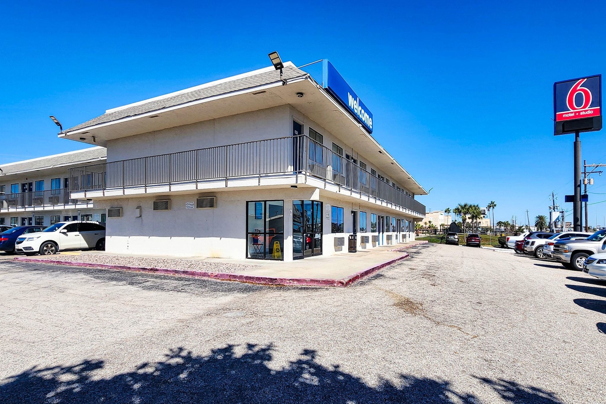 A motel with a blue sign, a parking lot, and a clear sky.