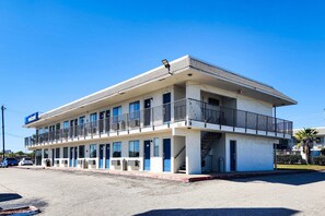 Un motel de dos pisos con techo plano, varios balcones y un letrero que dice 'Welcome'.