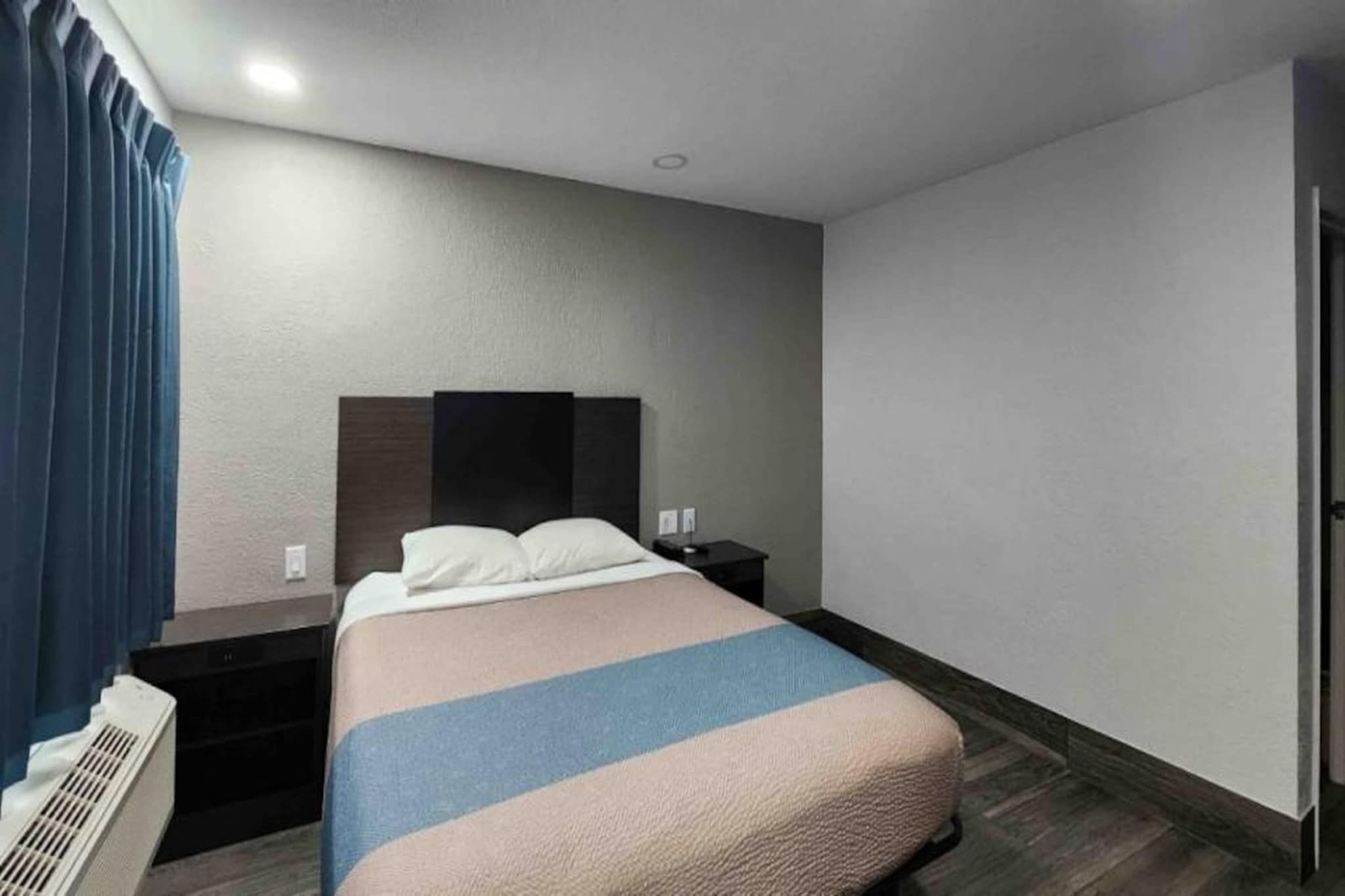 Habitació d'hotel amb un llit, una nit, un escalfador i una porta.
