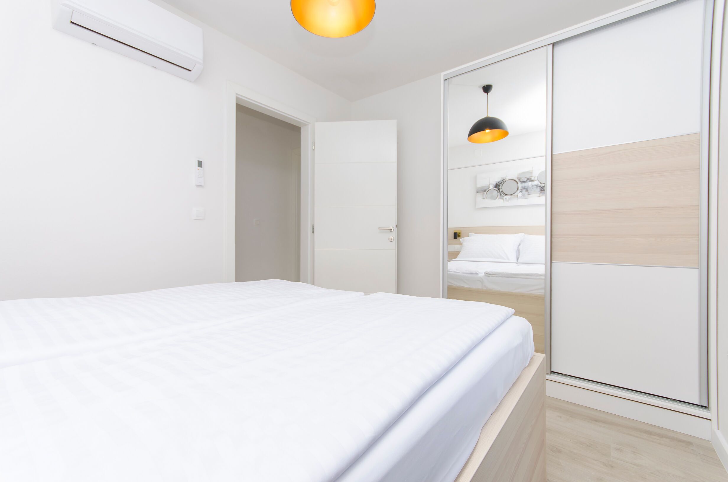 Un dormitorio moderno con cama, armario y una lámpara colgante.