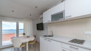 A modern kitchen with white cabinets, a stainless steel sink, and a built-in microwave. - Apartments Teresa (Seget)