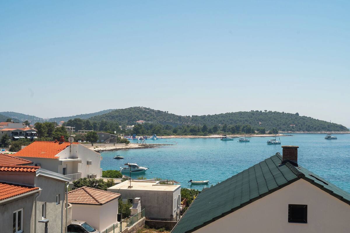 A coastal town with buildings, a beach, and boats in the water.