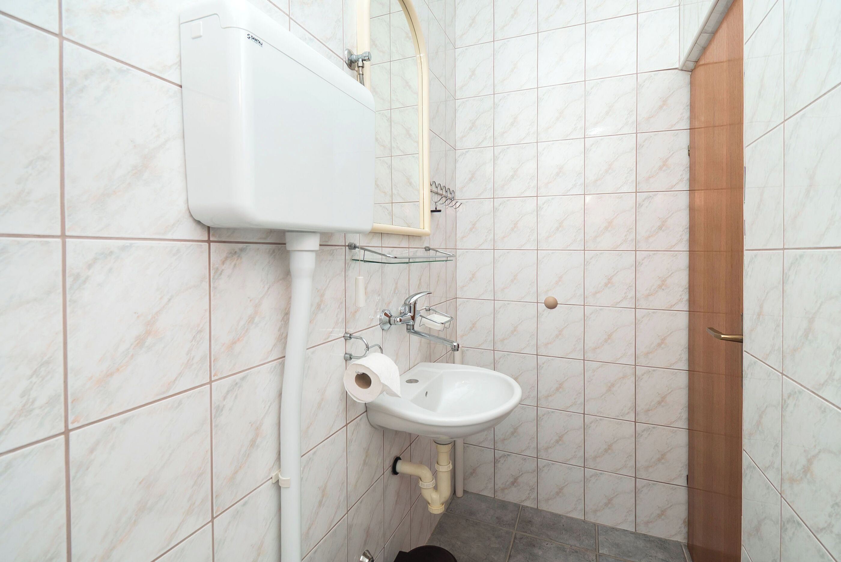 Une salle de bain avec un lavabo blanc, des toilettes et une porte en bois.