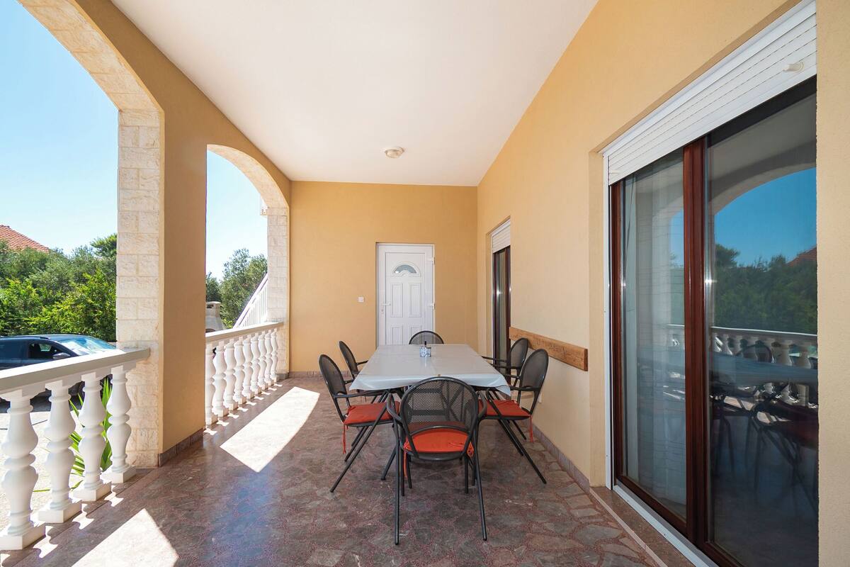 An outdoor balcony with a table and chairs, a white door, and a glass door leading to a balcony with chairs.