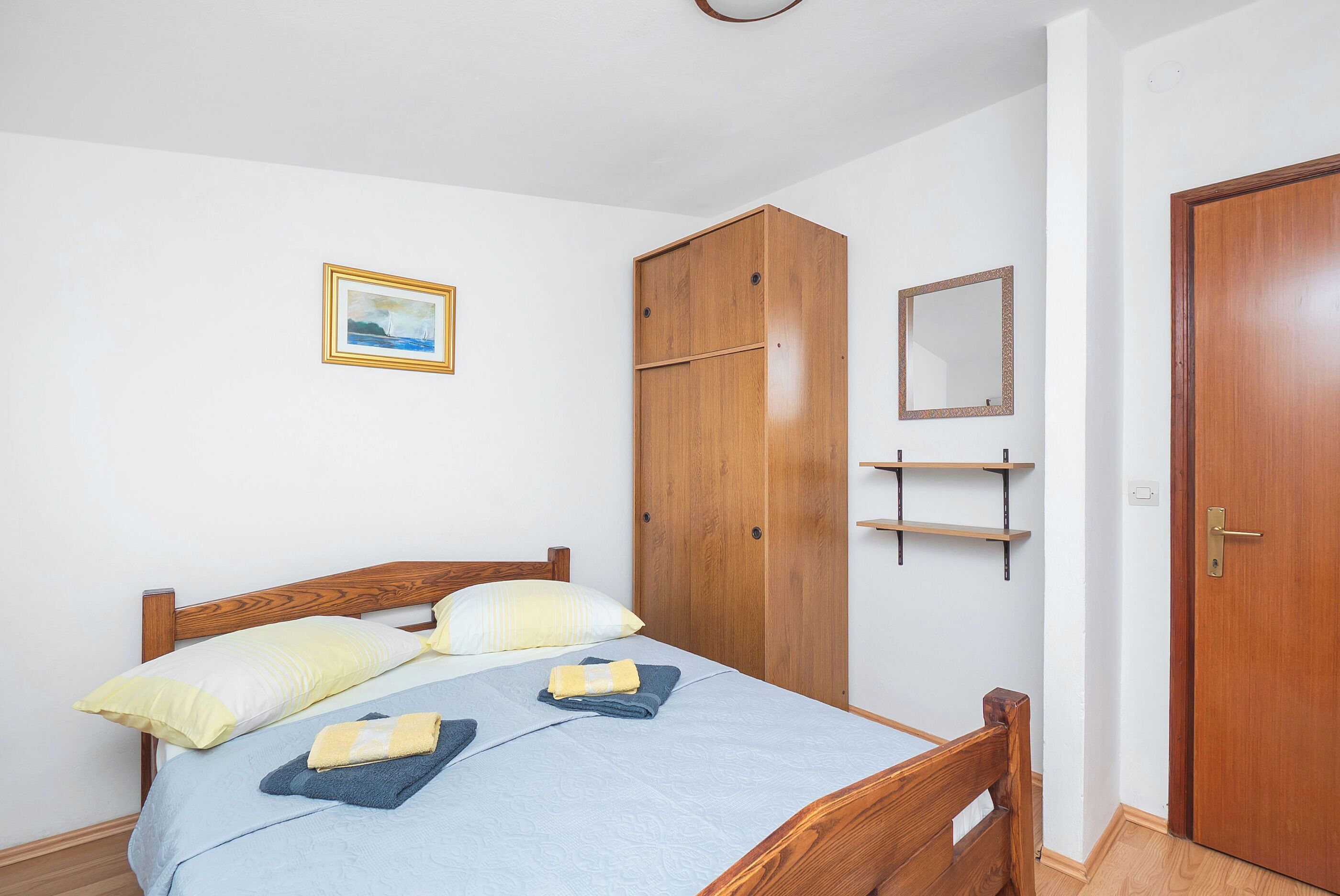Ein Schlafzimmer mit einem hölzernen Bett, einem Kleiderschrank, einem Spiegel und einer Tür.