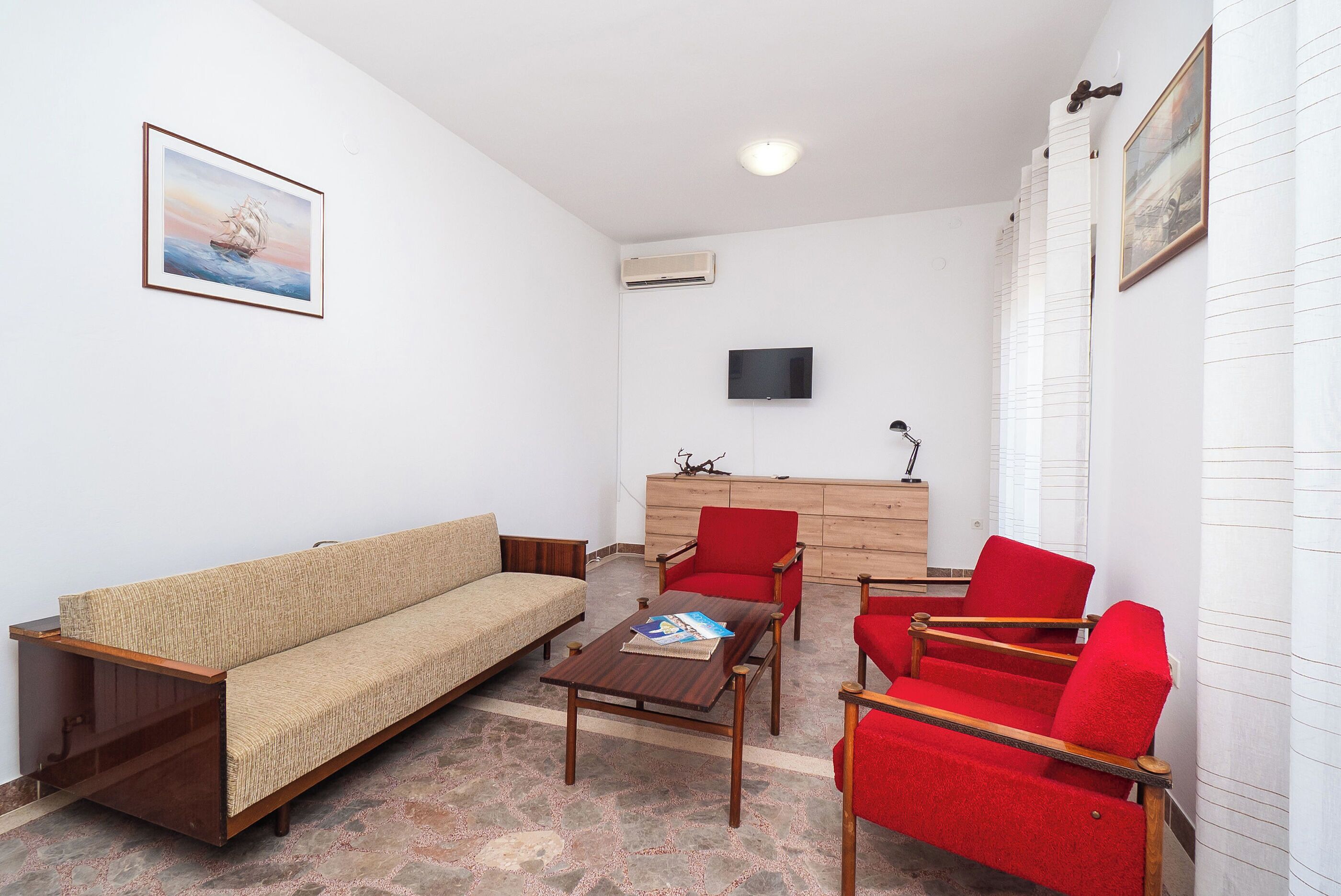 A living room with a sofa, a coffee table, and red chairs.